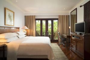 a bedroom with a bed and a desk and a television at Sheraton Senggigi Beach Resort in Senggigi