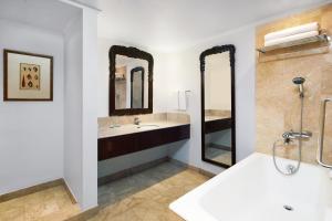 a bathroom with a tub and a sink and two mirrors at Sheraton Senggigi Beach Resort in Senggigi