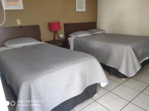 two beds sitting next to each other in a room at Hotel Caracoles Colima in Colima