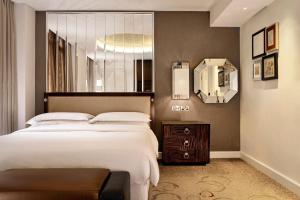 a bedroom with a large bed and a mirror at Sheraton Grand London Park Lane in London