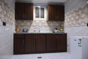 a kitchen with brown cabinets and a sink at جوهرة القنفذة in Al Qunfudhah