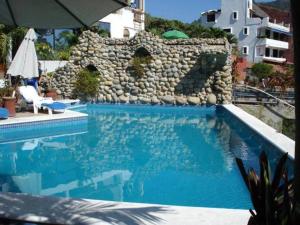 a swimming pool with a stone wall in the background at Vista Bahia Zihua in Zihuatanejo