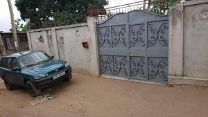 une voiture bleue garée devant une clôture dans l'établissement AUBERGE-NGOMSON, à Brazzaville
