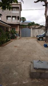 un estacionamiento con un coche estacionado frente a una casa en AUBERGE-NGOMSON, en Brazzaville