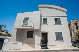 a white house with a balcony on top of it at Scirocco Holiday House LIMONE in Rosolini +25 photos