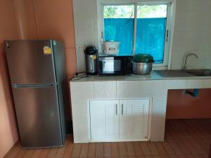 a kitchen with a stainless steel refrigerator and a window at แสงหิรัญ บีช รีสอร์ท in Pran Buri