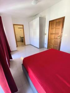 Schlafzimmer mit einem roten Bett und einer Holztür in der Unterkunft Attico sul Mare in Vibo Valentia Marina