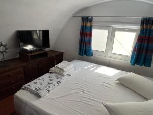 1 dormitorio con 1 cama, TV y ventana en Sunset view apartment en Oia