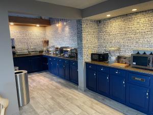 a large kitchen with blue cabinets and brick walls at AmericInn by Wyndham Chippewa Falls in Chippewa Falls