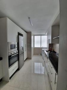 uma grande cozinha com armários e electrodomésticos brancos em Preciosoy gran apartamento terraza con vistas wifi y climatización em Málaga