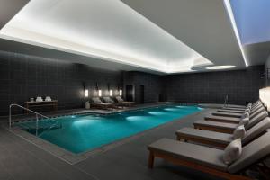 奈良市にあるJWマリオット・ホテル奈良のラウンジチェアとスイミングプール付きのホテルルーム内のプールを提供しています。