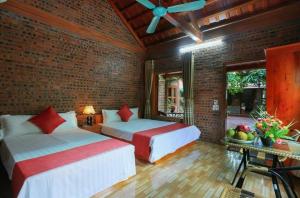 1 dormitorio con 2 camas y pared de ladrillo en Tam Family Homestay, en Ninh Binh