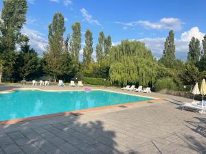 une grande piscine avec des chaises et des arbres dans l'établissement Carresi Apart 2 pax with pool - portable A/C, à Figline Valdarno
