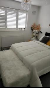 巴塞爾頓的住宿－Private luxurious space，卧室配有一张带吊灯的大型白色床。