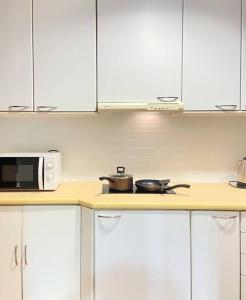 a kitchen with white cabinets and a microwave on a counter at Baan Nonzee Condo Kingsize bed Big room in Sathorn in Bangkok