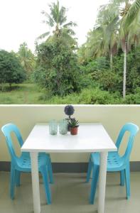 uma mesa branca e cadeiras azuis em frente a uma janela em Casa Michabella Leisure and Events Place em Supa