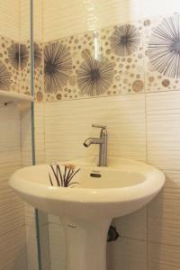 um lavatório branco numa casa de banho com flores na parede em Casa Michabella Leisure and Events Place em Supa