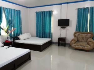 a room with two beds and a chair and a television at Casa Michabella Leisure and Events Place in Supa