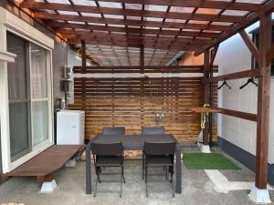 eine Terrasse mit einem Tisch, Stühlen und einer Bank in der Unterkunft 日向サーフキャンプ210 in Hyuga