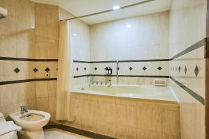 ein Bad mit einer Badewanne und einem WC in der Unterkunft Horison Ultima Menteng Jakarta in Jakarta