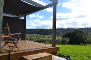 uma cadeira sentada num deque com vista para um campo em Manuka Views - Close to Thermal Hot Pools em Kaukapakapa