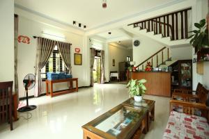 a large living room with a glass table and stairs at Hoi An Holiday Villa in Hoi An