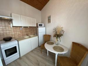 a small kitchen with a table and a white refrigerator at Appartement cosy à Fouras: 1 chambre, proche commerces et plages, Wifi, TV, cuisine équipée - FR-1-709-70 in Fouras