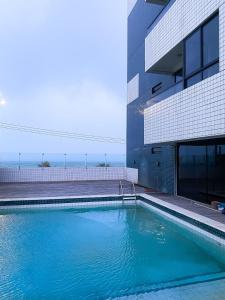 a swimming pool in front of a building at Acomodação aconchegante à beira- mar in Natal