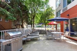 eine Terrasse mit einem Grill, Stühlen, Tischen und Sonnenschirmen in der Unterkunft SpringHill Suites Rochester Mayo Clinic Area / Saint Marys in Rochester