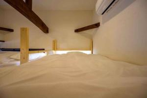uma grande cama branca num pequeno quarto em 日向サーフキャンプ211 em Hyuga