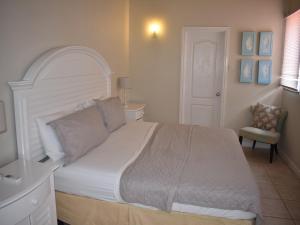 sypialnia z dużym białym łóżkiem i krzesłem w obiekcie Harbour View Penthouse w mieście Gros Islet