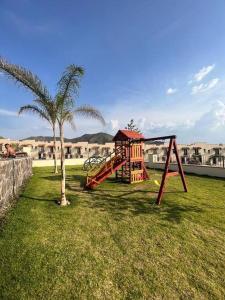 un parque infantil con columpios y una palmera en Hermosa casa, sur de Guadalajara, en Guadalajara