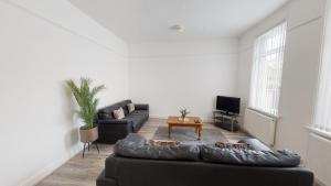 ein Wohnzimmer mit einem schwarzen Sofa und einem TV in der Unterkunft City Centre-University Home from Home in Sunderland