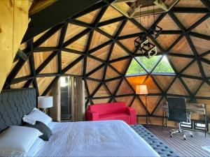 a bedroom with a bed and a red chair in a room at Entre-pinos Glamping WiFi Vista 360º in Guarne