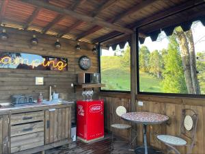 una cocina al aire libre con una máquina de coca cola y una mesa en Entre-pinos Glamping WiFi Vista 360º, en Guarne