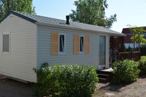 a white tiny house with brown shutters on it at Camping Valencia el Saler in El Saler