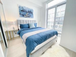 um quarto com uma cama com lençóis azuis e uma janela em Boutique Penthouse-Live in the SKY with Amazing Lakeview! Downtown Toronto!B em Toronto