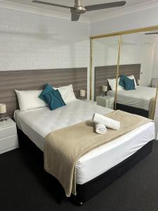 Una habitación de hotel con dos camas con almohadas azules. en Bribie Waterways Motel, en Bongaree