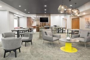 a waiting room with tables and chairs and a tv at SpringHill Suites by Marriott Tulsa in Tulsa