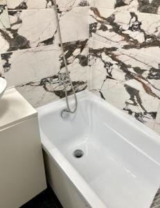 a white bath tub in a bathroom with marble tiles at Grīzupes apart in Liepāja