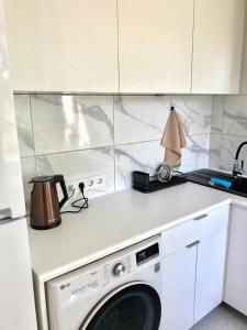 een keuken met een wasmachine in een witte keuken bij Grīzupes apart in Liepāja