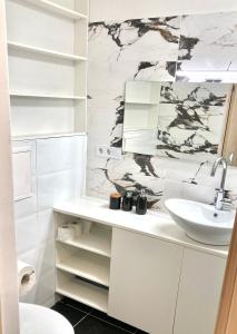 Baño blanco con lavabo y espejo en Grīzupes apart, en Liepāja