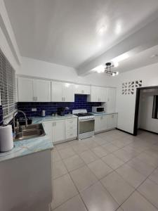 a large kitchen with white cabinets and blue tile floors at Chalet Belizomi Tropical Villa #1 in Gros Islet
