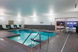 a swimming pool in a building with chairs and tables at SpringHill Suites by Marriott Salt Lake City Airport in Salt Lake City