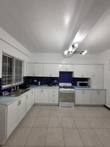 una cocina vacía con armarios y electrodomésticos blancos en Chalet Belizomi Tropical Villa #1 en Gros Islet