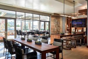 een restaurant met houten tafels, stoelen en ramen bij Marriott Irvine Spectrum in Irvine
