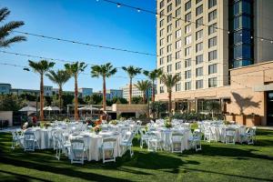 a group of tables with white chairs and palm trees at Marriott Irvine Spectrum in Irvine