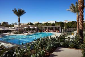 a large swimming pool with chairs and palm trees at Marriott Irvine Spectrum in Irvine
