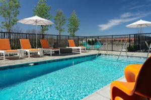 a swimming pool with orange chairs and umbrellas next to a pool at Aloft Knoxville West in Knoxville