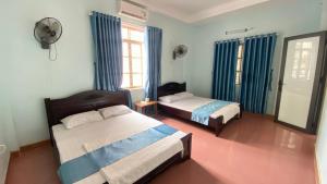 1 dormitorio con 2 camas y cortinas azules en Cat Ba Life Hostel en Hai Phong
